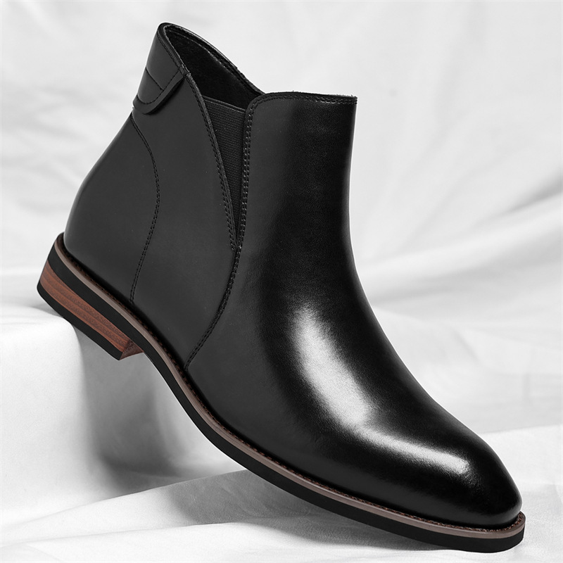 A black leather Chelsea boot with an elastic side panel, shown at an angle on a white sheet.