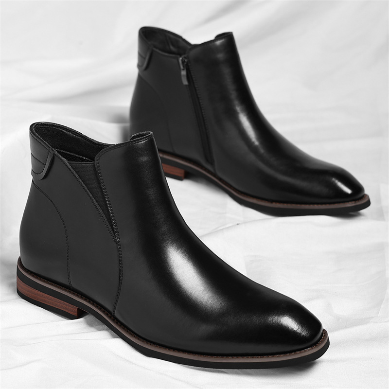 Pair of black leather Chelsea boots with side zippers, standing together on a white sheet.