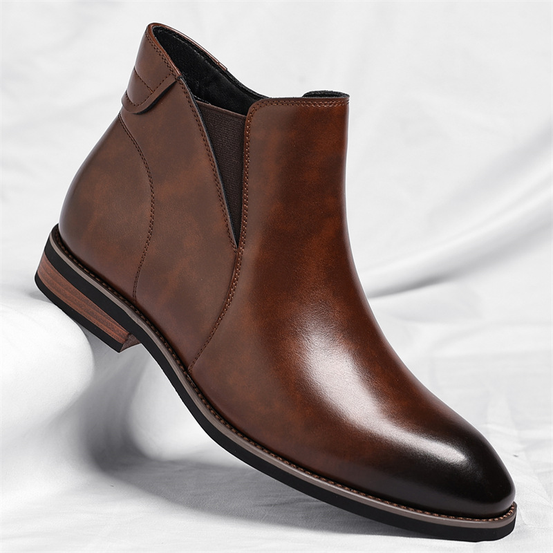 A brown leather Chelsea boot with an elastic side panel, shown at an angle on a white sheet.