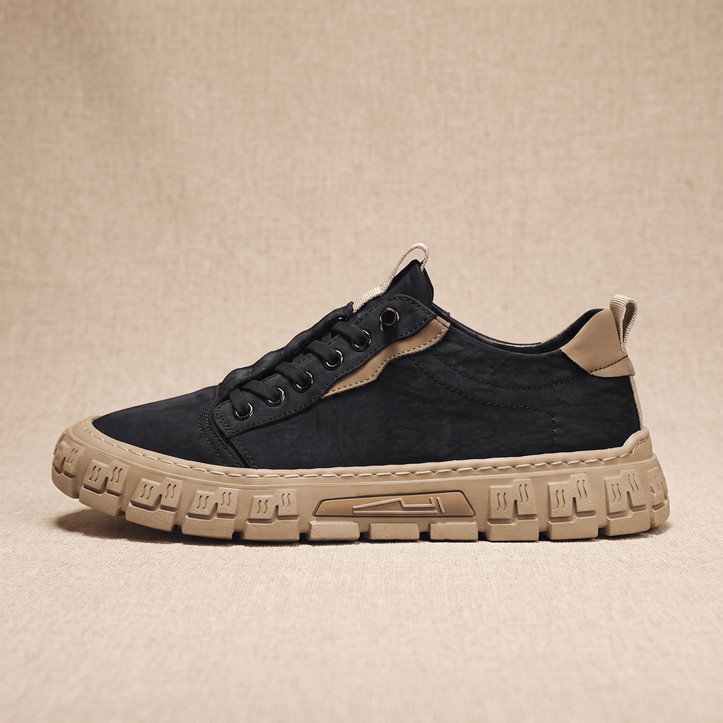 Side profile view of a black canvas sneaker with tan heel patch and tan treaded sole on a beige backdrop