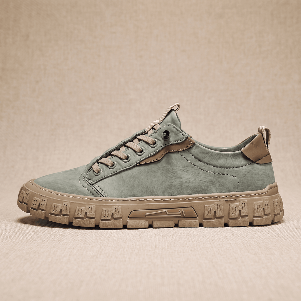 Side profile view of a sage green suede sneaker with tan heel patch and chunky treaded gum sole on a beige backdrop