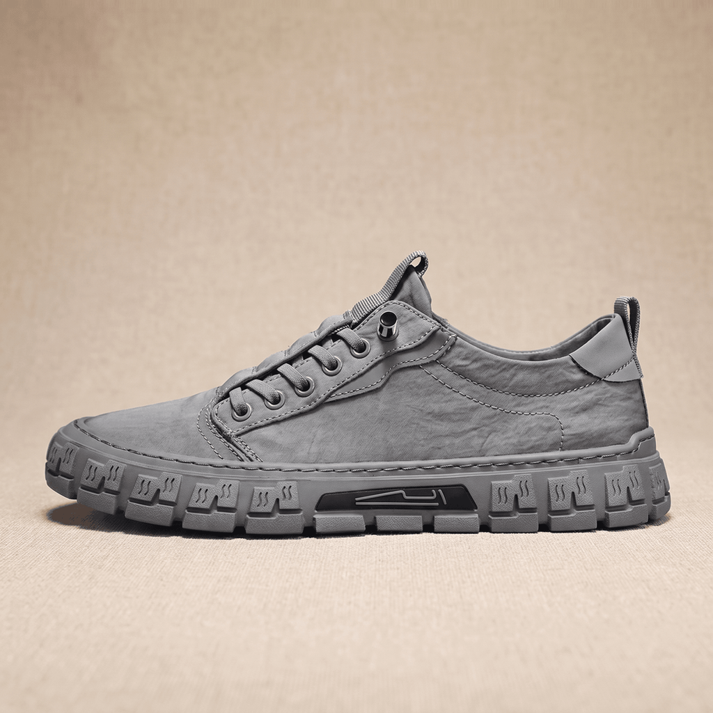 Side profile view of a gray canvas sneaker with treaded gum sole on a beige backdrop