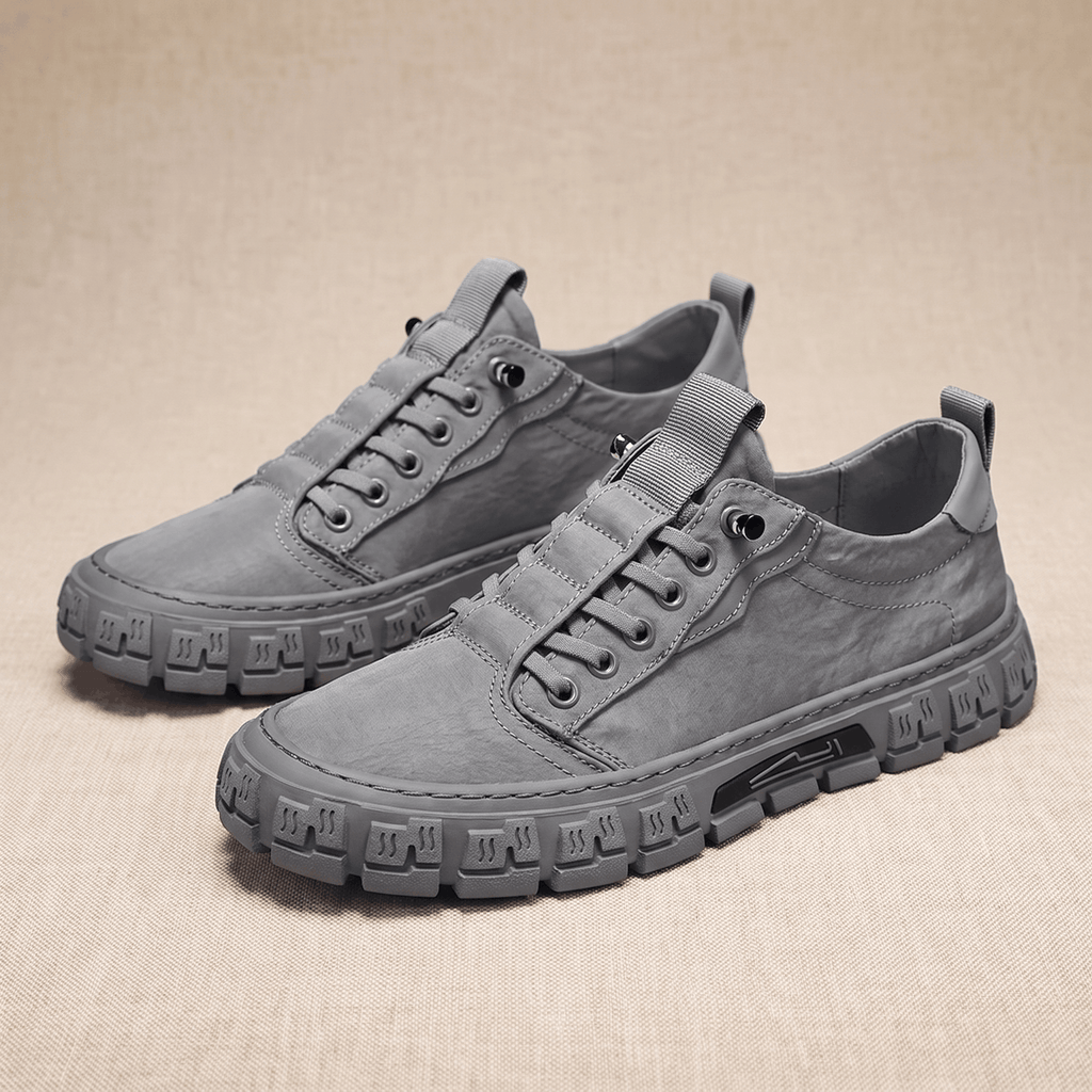 Pair of gray canvas sneakers with treaded gum soles arranged side by side on a beige fabric backdrop