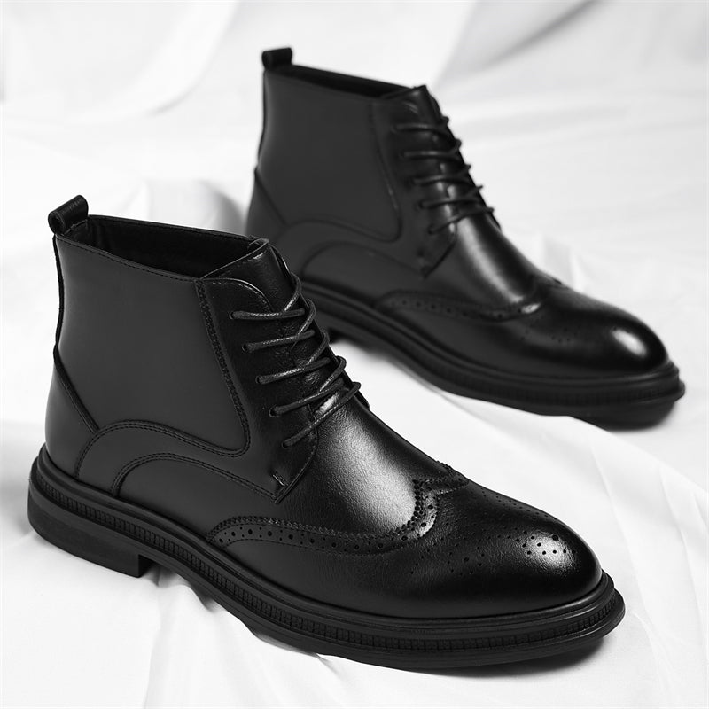 Pair of black leather brogue ankle boots with wingtip perforation detailing, standing together on a white sheet.