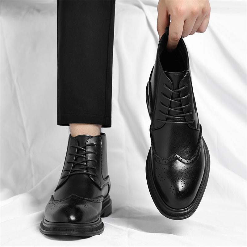 A model wearing one black leather brogue boot while holding the other by its pull tab, standing on a white sheet.