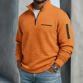 Burnt orange waffle-knit quarter-zip sweater with a relaxed fit, black zipper details, and a textured grid surface.