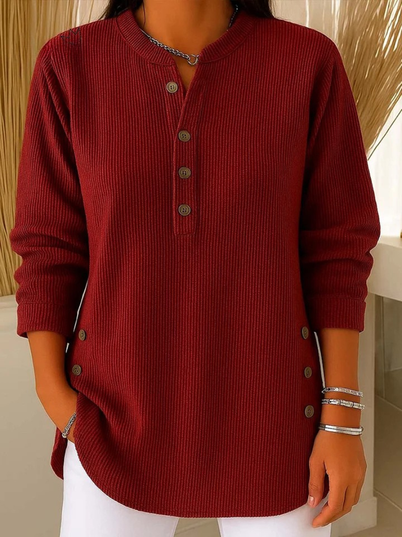 Woman wearing a burgundy waffle knit Henley sweater featuring a split neckline, button placket, side button accents, and long sleeves.
