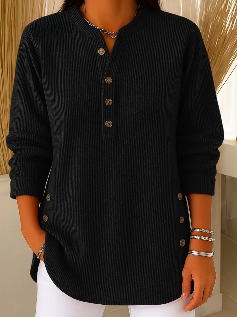 Woman wearing a black waffle knit Henley sweater with a split neckline, decorative buttons, long sleeves, and a relaxed fit.