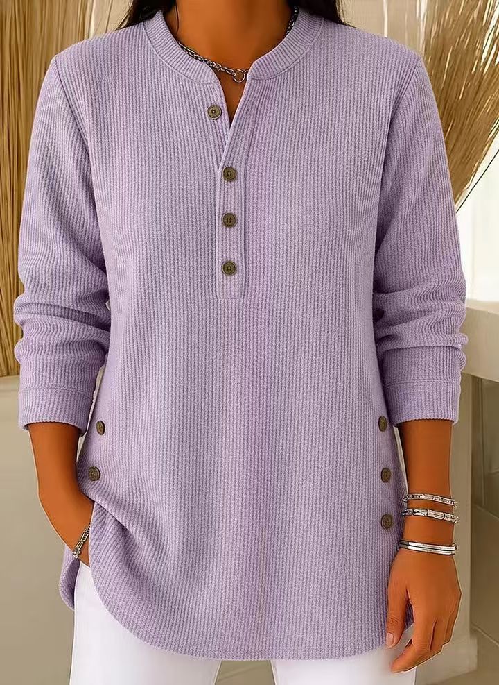 Woman wearing a purple waffle knit Henley sweater featuring a split neckline, button placket, side button details, and a relaxed fit.