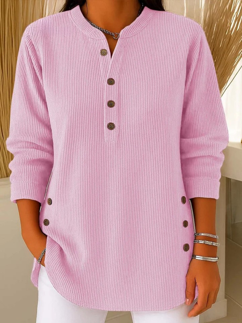 Woman wearing a pink waffle knit Henley sweater with a split neckline, decorative button placket, long sleeves, side button details, and a relaxed fit.