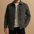 Man wearing a black and white plaid textured overshirt jacket over a white tee, paired with dark trousers.