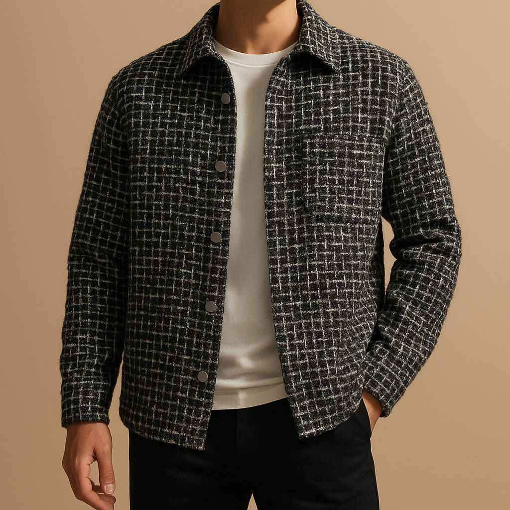 Man wearing a black and white plaid textured overshirt jacket over a white tee, paired with dark trousers.