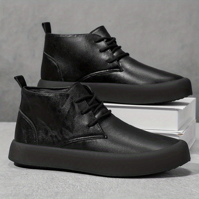 Pair of black leather chukka-style boots, one shoe propped on a white platform box, against a gray background.
