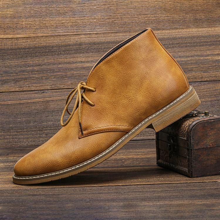 A single tan leather lace-up chukka boot propped against a small wooden chest, close-up side view.