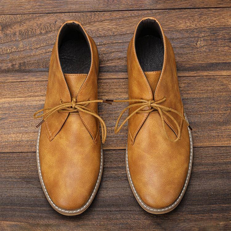 Symmetrical overhead view of a pair of tan leather chukka boots standing upright side by side on a wooden surface.