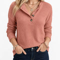 Woman wearing a pink waffle knit Henley sweater with a V-neck button placket, long sleeves, and a relaxed fit.