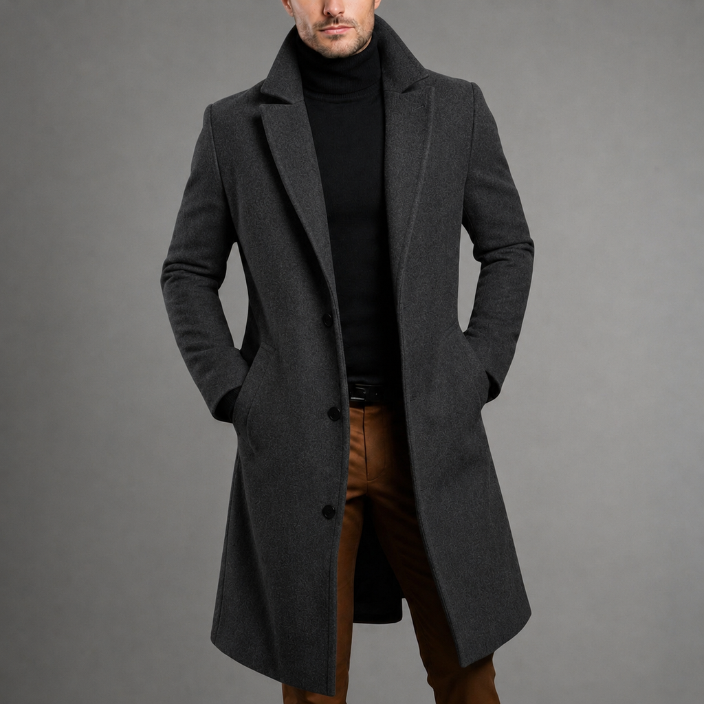 Dark gray wool blend longline overcoat in a slim fit with a classic button-front, layered over a black turtleneck.