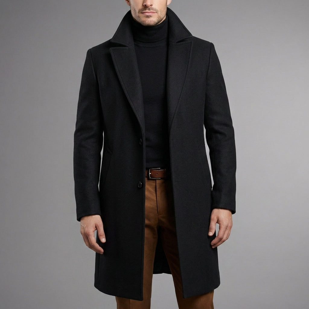 Slim-fit black wool blend longline overcoat with a classic button-front, worn over a black turtleneck and brown trousers.