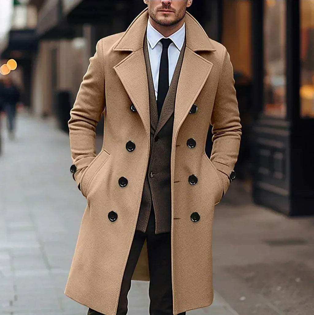 Camel wool double-breasted trench coat with structured lapels and black buttons, worn over a tailored suit on a city street.