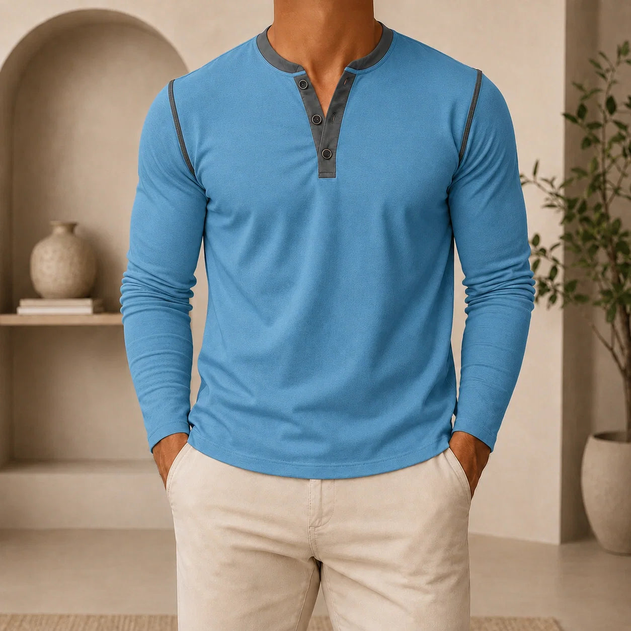 Man wearing a light blue long-sleeve Henley sweater with a contrast navy placket, ribbed cuffs, and classic slim fit.