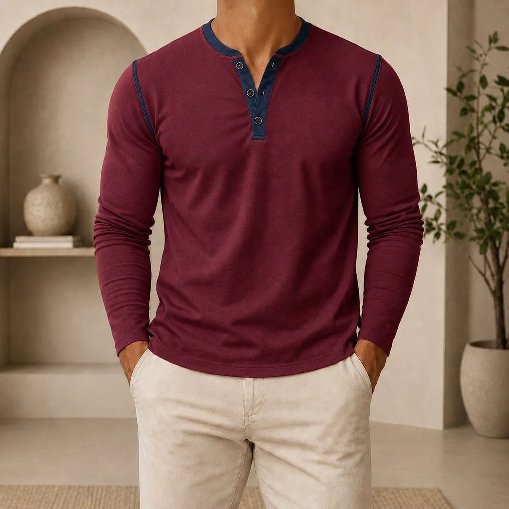Man wearing a burgundy long-sleeve Henley sweater featuring a contrast navy placket, three-button neckline, and modern slim fit.