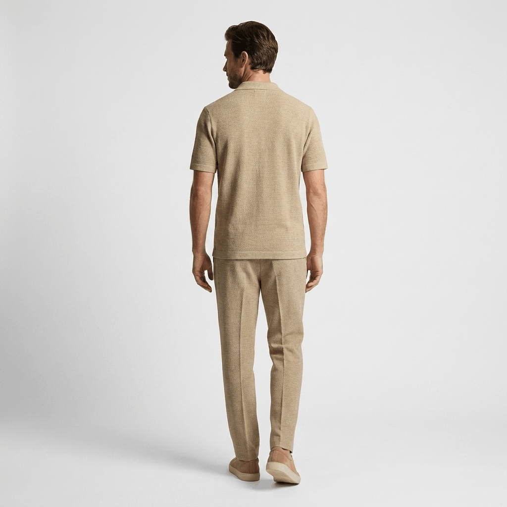 Back view of a man wearing a beige cotton short-sleeve shirt with matching linen trousers.