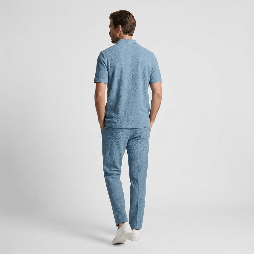 Back view of a man wearing a light blue cotton short-sleeve shirt with matching linen trousers.