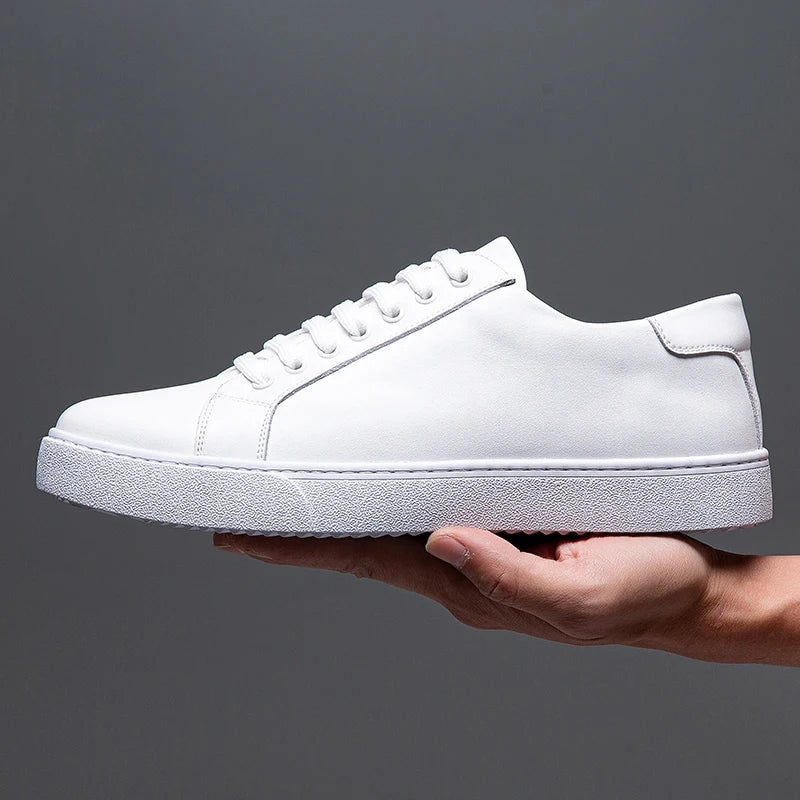 Hand holding a single white leather Zoren sneaker, showing side profile with matching white sole