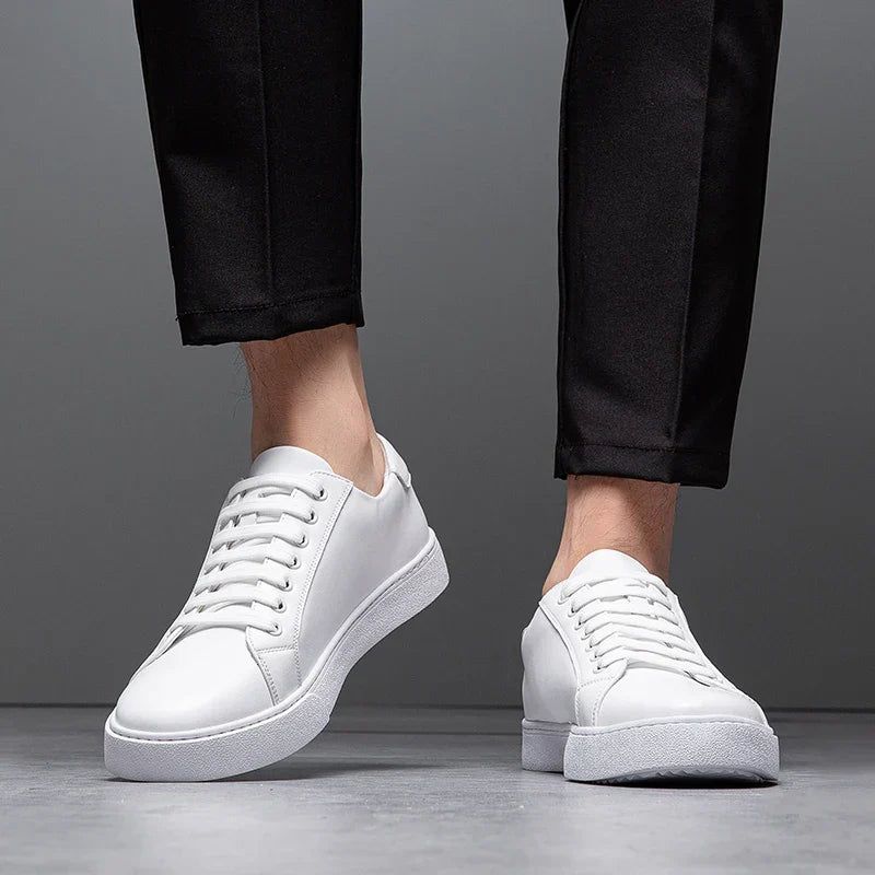 Close-up of man's legs in black trousers wearing white leather Zoren sneakers