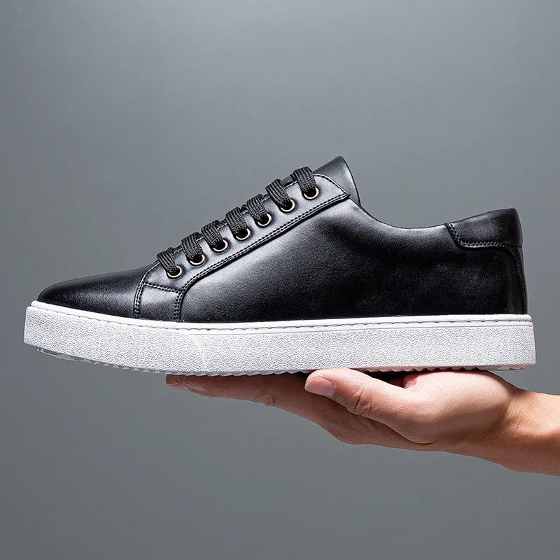 Hand holding a single black leather Zoren sneaker, showing side profile with white sole
