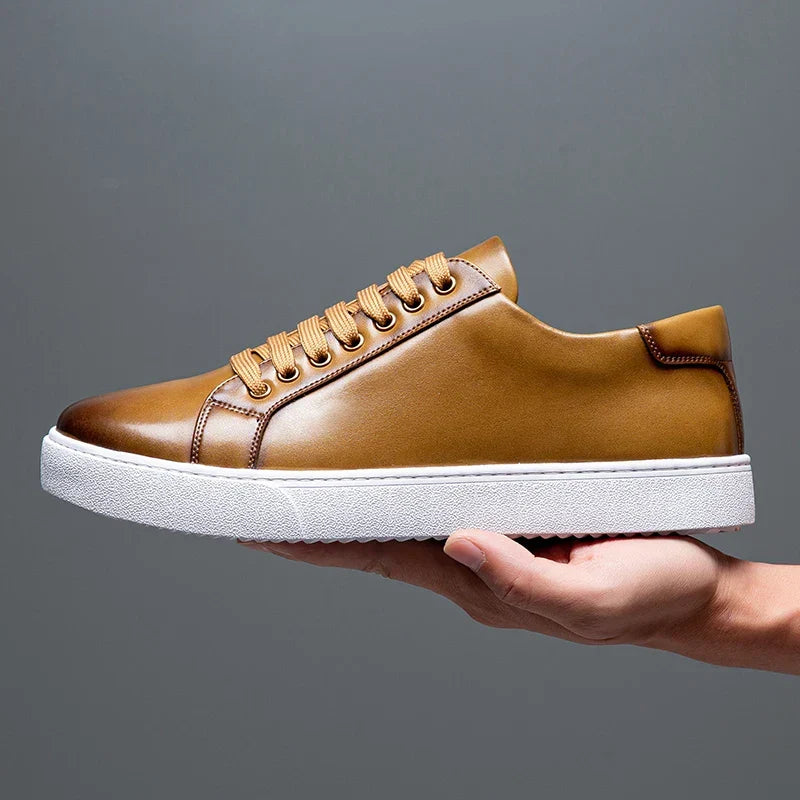 Hand holding a single tan leather Zoren sneaker, showing side profile with white sole